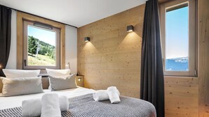 Un dormitorio con una cama grande, dos lámparas de noche, una ventana con vistas a un paisaje y una pared de madera.