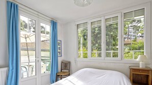 Un dormitorio con una cama grande, una ventana que da a zonas verdes y una silla cerca de la ventana.