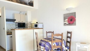 A compact kitchen with a dining area, including a table with a patterned tablecloth and wooden chairs.