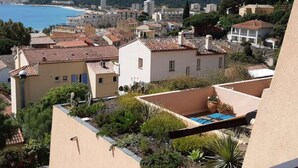A residential area with Mediterranean architecture, a pool, and a view of the sea.