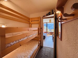 A bunk room with wooden bunk beds and a door leading to a balcony with a mountain view.