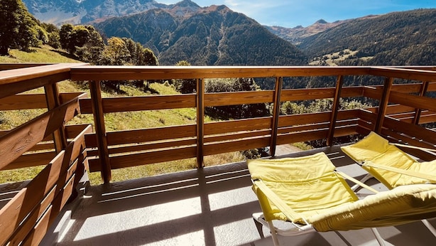 Un balcon doté de balustrades en bois, offrant une vue sur un paysage montagneux.