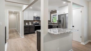 Una cocina moderna con armarios blancos, electrodomésticos de acero inoxidable y encimera de granito.
