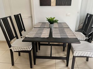 Six people can dine comfortably around the table, surrounded by stylish chairs and a decorative wall piece.