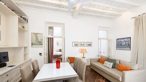 Una sala de estar moderna con una mesa de comedor, sofá y televisor sobre un mueble.