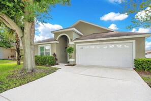 A single-story house with a garage, a driveway, and a tree in the front yard.