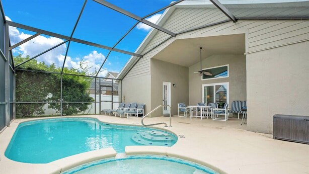 A swimming pool with lounge chairs and a covered patio area.