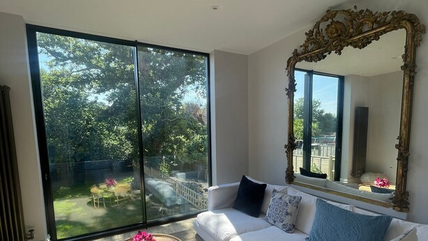A modern living room with a white sofa, a round coffee table, and a large mirror. - Stunning 6-Bedroom House in Swanage, Minutes from Beach, with Parking and Garden (Swanage)