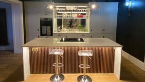 A modern kitchen with a central island, pendant lighting, and a built-in oven. - Stunning 6-Bedroom House in Swanage, Minutes from Beach, with Parking and Garden (Swanage)