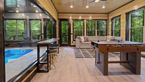 A modern interior with a pool, seating area, and a foosball table. - Rustic Cabin Retreat・Sleeps 10・Indoor Pool・Hot Tub (Sevierville)
