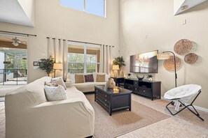 A spacious living room with a large window, a sofa set, a coffee table, and a flat-screen TV mounted on the wall. - ⭐ Stunning 6 Bed 5 bath Villa | 4 King Ensuite's | Private Pool | Gated Resort ⭐ (Davenport)