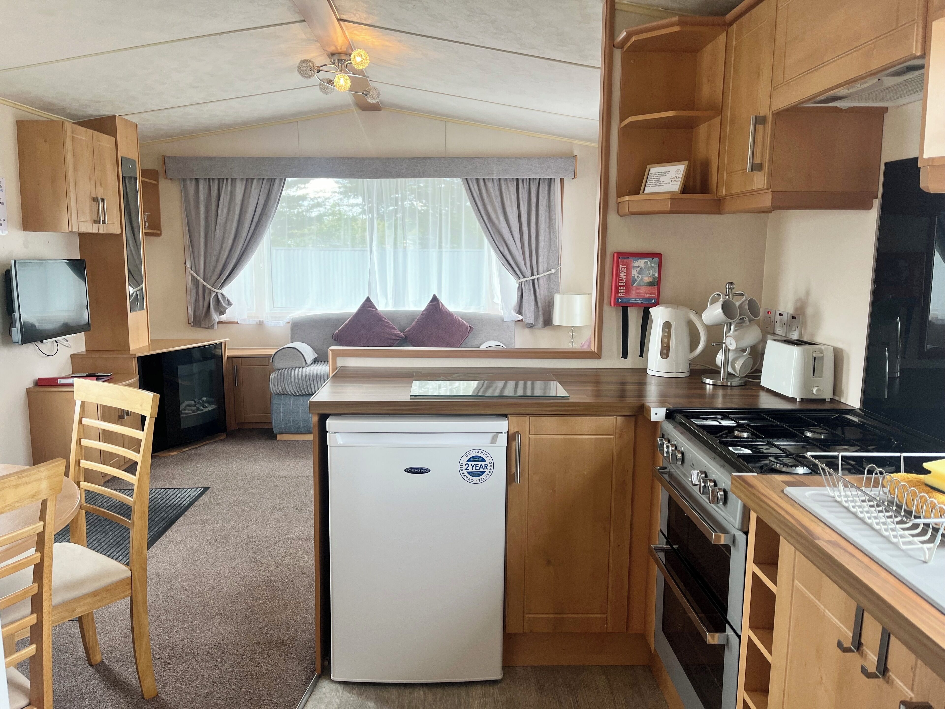 A compact kitchen with a refrigerator, stove, and a dining area with a chair and table.