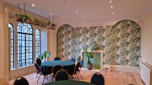 Un coin repas avec une table ronde, des chaises, des plantes en pot et un mur décoré de motifs.