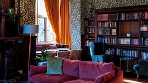 Une bibliothèque avec un canapé rouge, des étagères et un lustre.