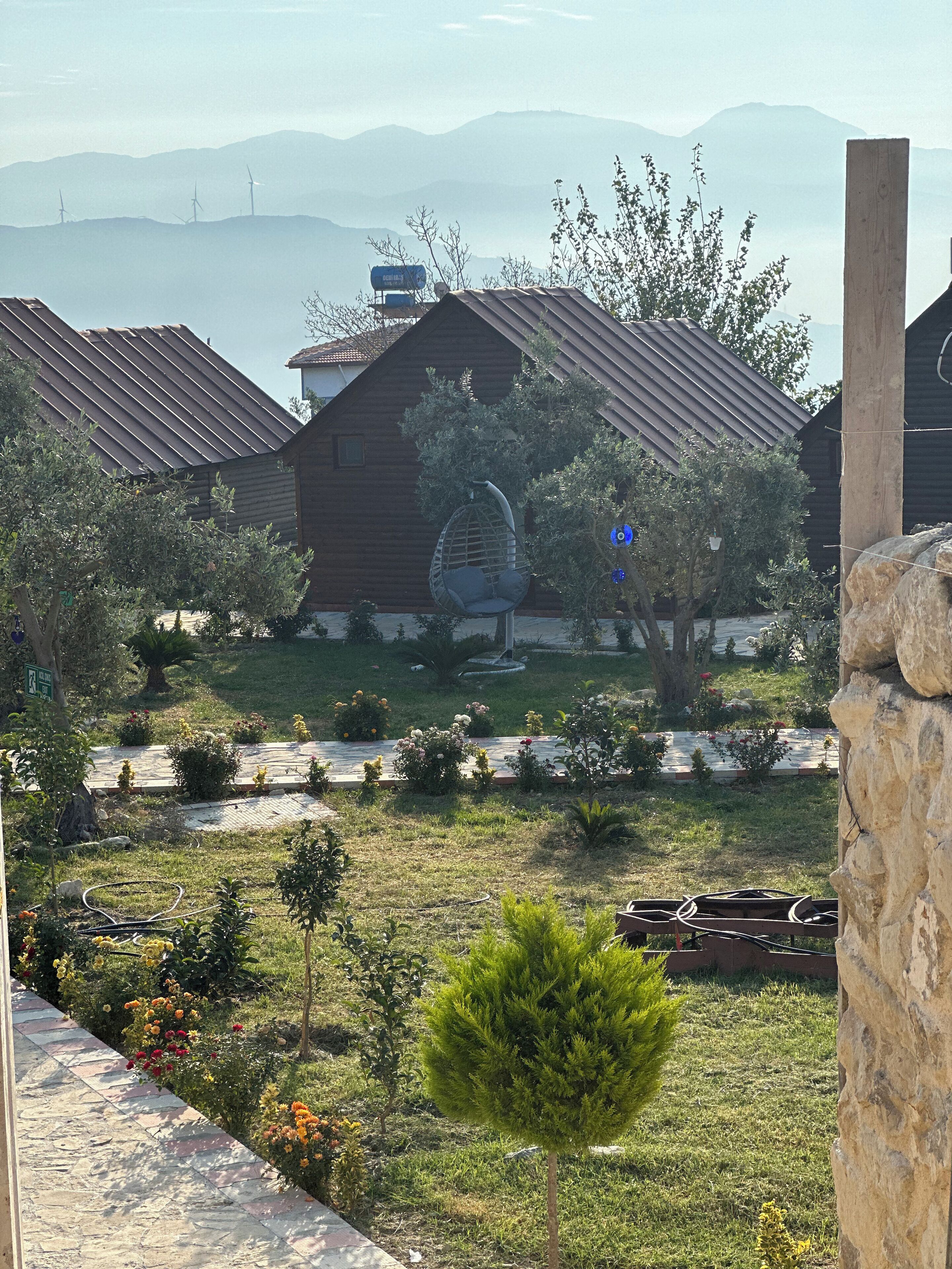 A rustic wooden house with a sloped roof, surrounded by a well-maintained garden with various plants and flowers.