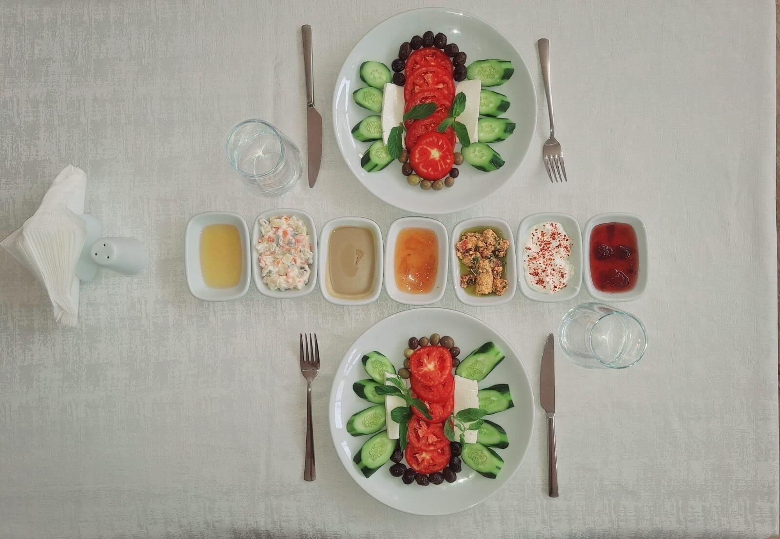 Una mesa dispuesta con dos platos de comida, cada uno con una variedad de verduras y un recipiente pequeño de salsa.