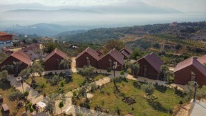 A cluster of brick houses with red roofs, arranged in a row with a paved pathway in between. - LUNA HOME CLUB (Samandagi)