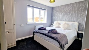 Ein Schlafzimmer mit Bett, Fenster, Heizkörper und Kleiderschrank.