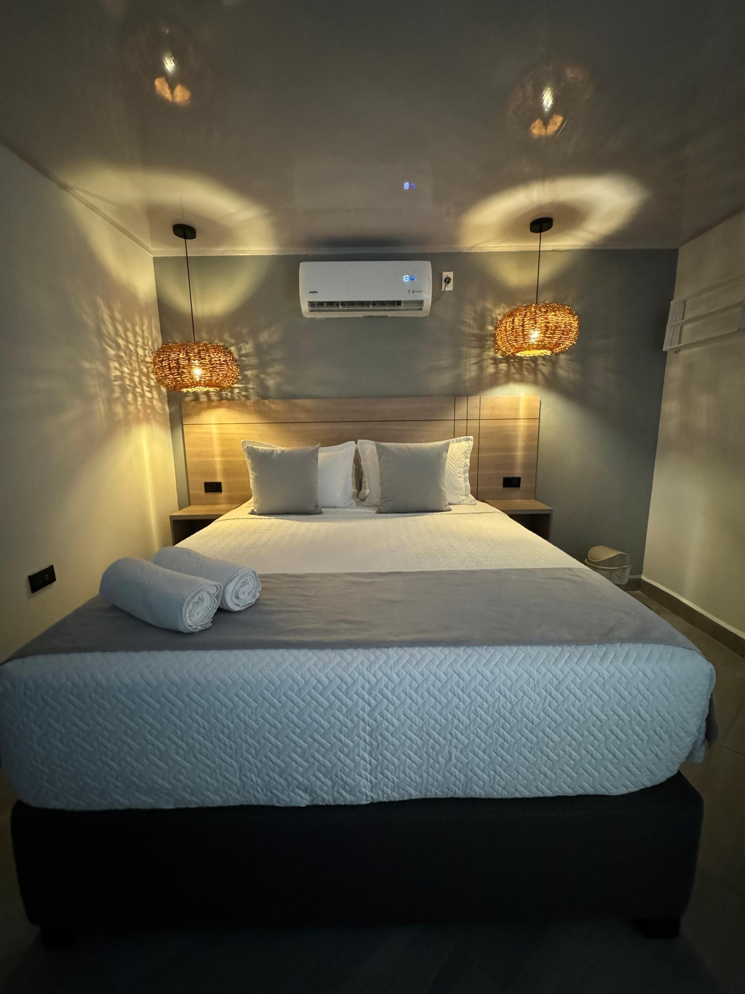Una camera da letto con un letto grande, due lampade ai comodini, un condizionatore d'aria e un punto luce a parete.