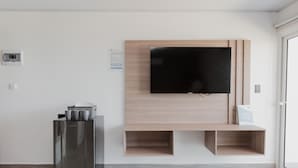 Una sala moderna con un televisor de pantalla plana montado en una pared de madera, una cafetera integrada y un diseño minimalista.