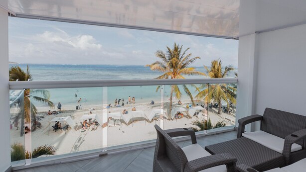 Un balcón con vista a una playa y palmeras.