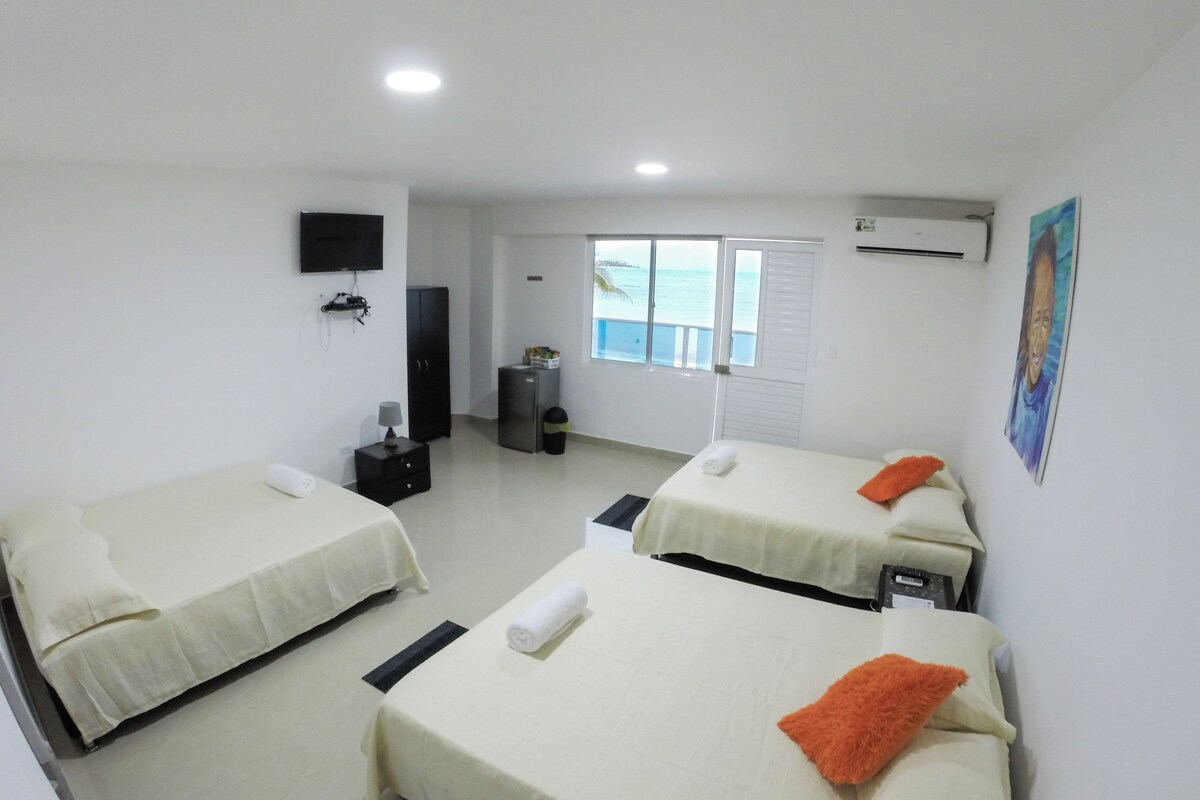 Une chambre d’hôtel avec deux lits, une télévision, une armoire, une petite table et une fenêtre donnant sur la mer.