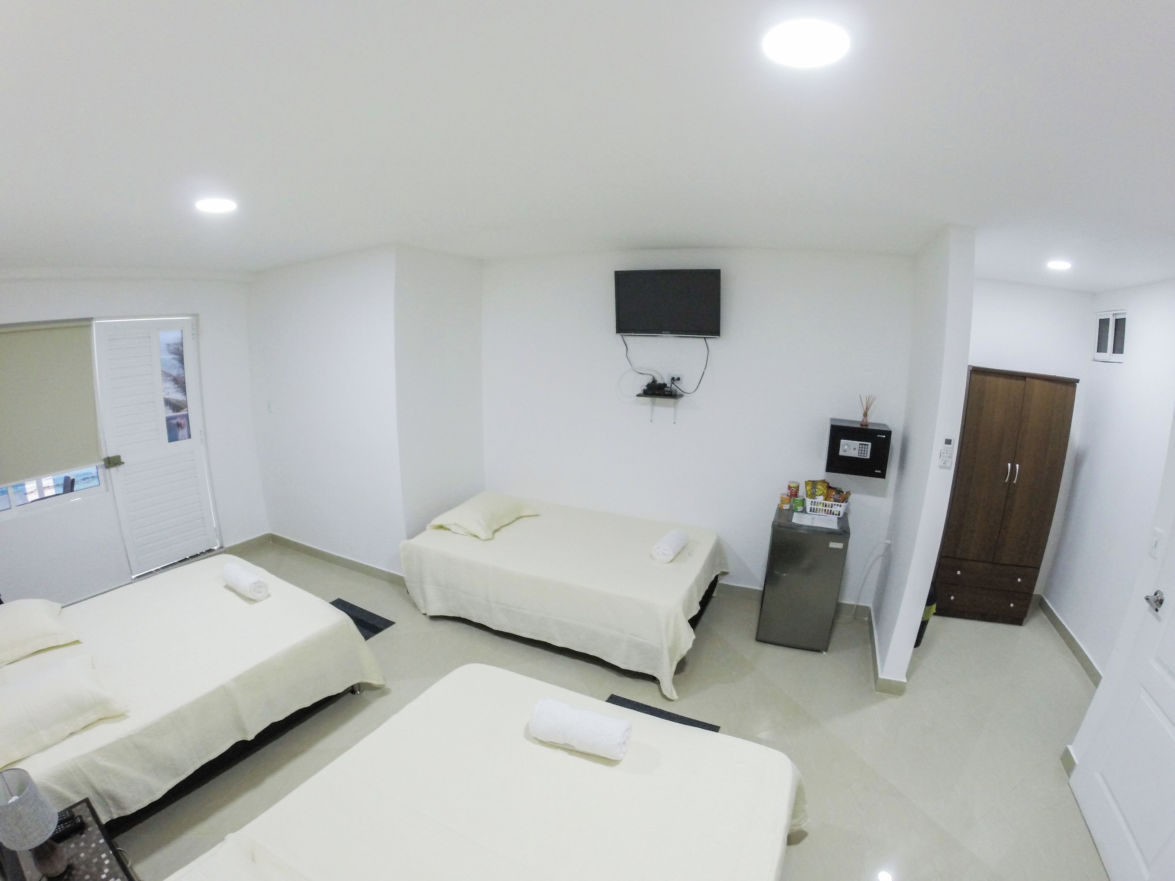 Una camera d'albergo con due letti, televisione, minibar e armadio.