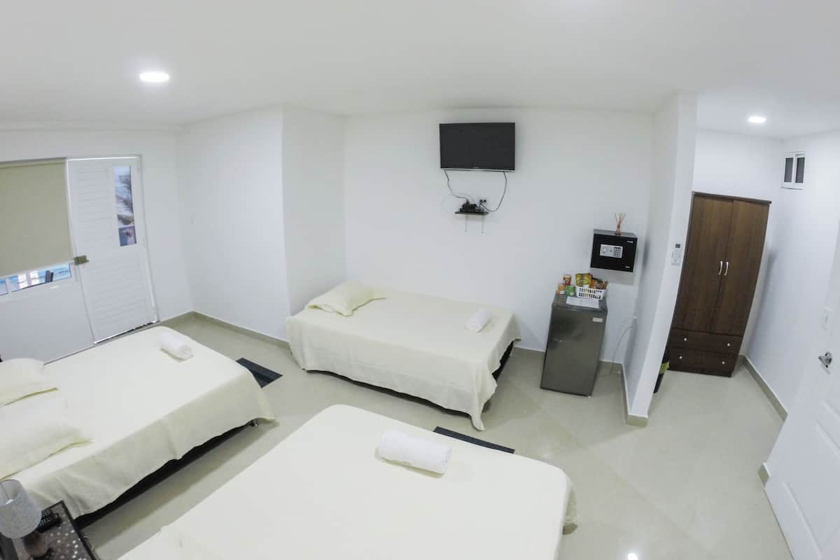 Quarto de hotel com duas camas, televisão, minibar e guarda-roupa.