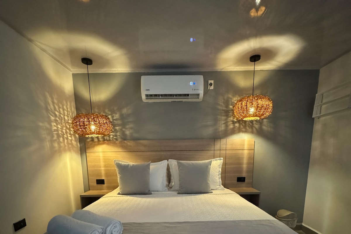 Une chambre à coucher avec un grand lit, deux lampes de chevet, un appareil de climatisation et un luminaire fixé au mur.