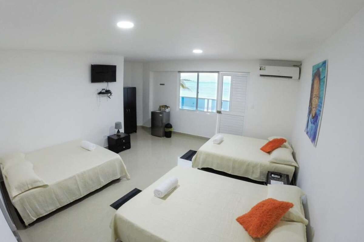 A hotel room with two beds, a TV, an air conditioner, and a window with a view.