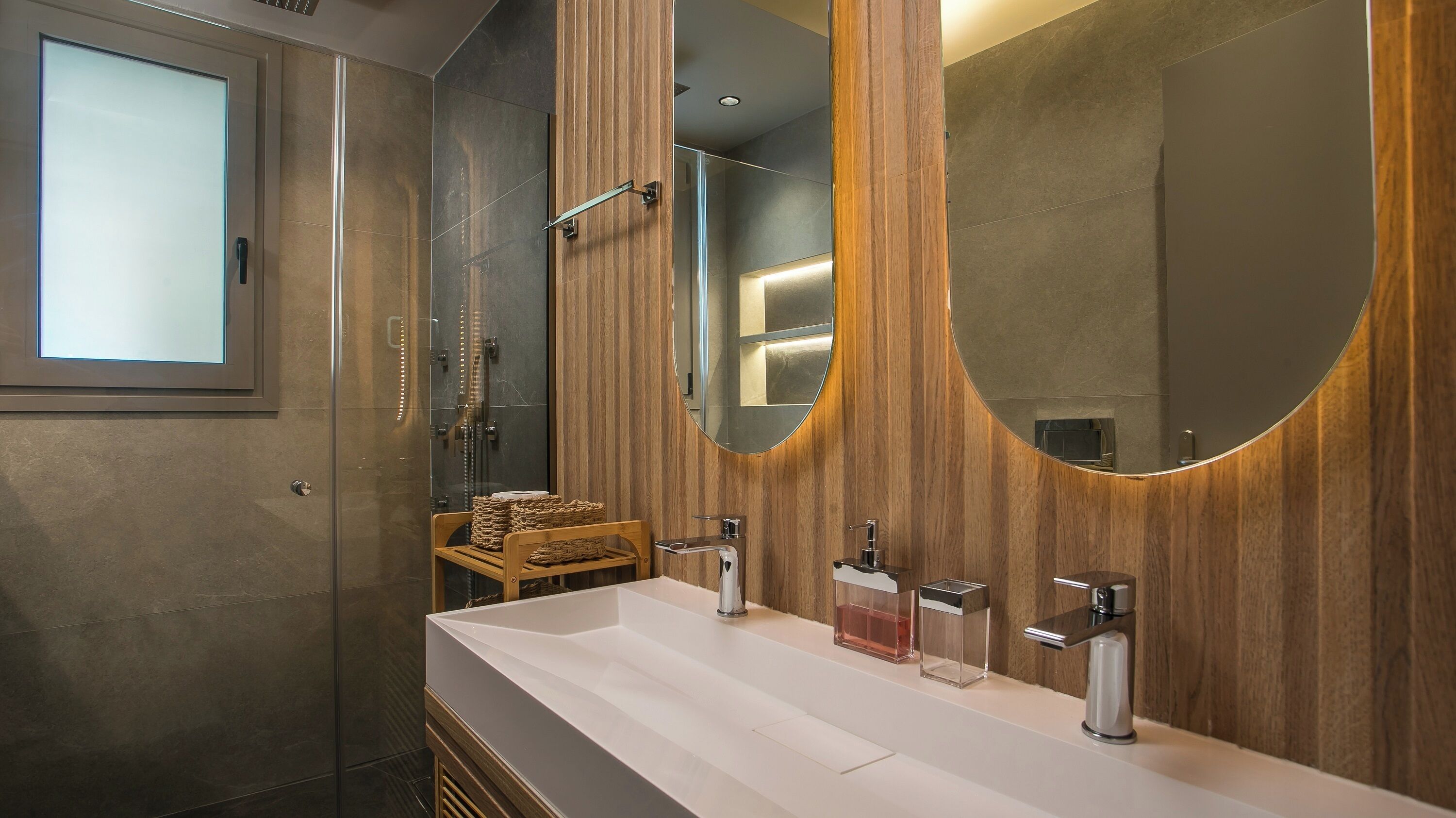 Une salle de bain moderne dotée d’un grand miroir, d’une cabine de douche et d’un meuble-lavabo avec deux vasques.