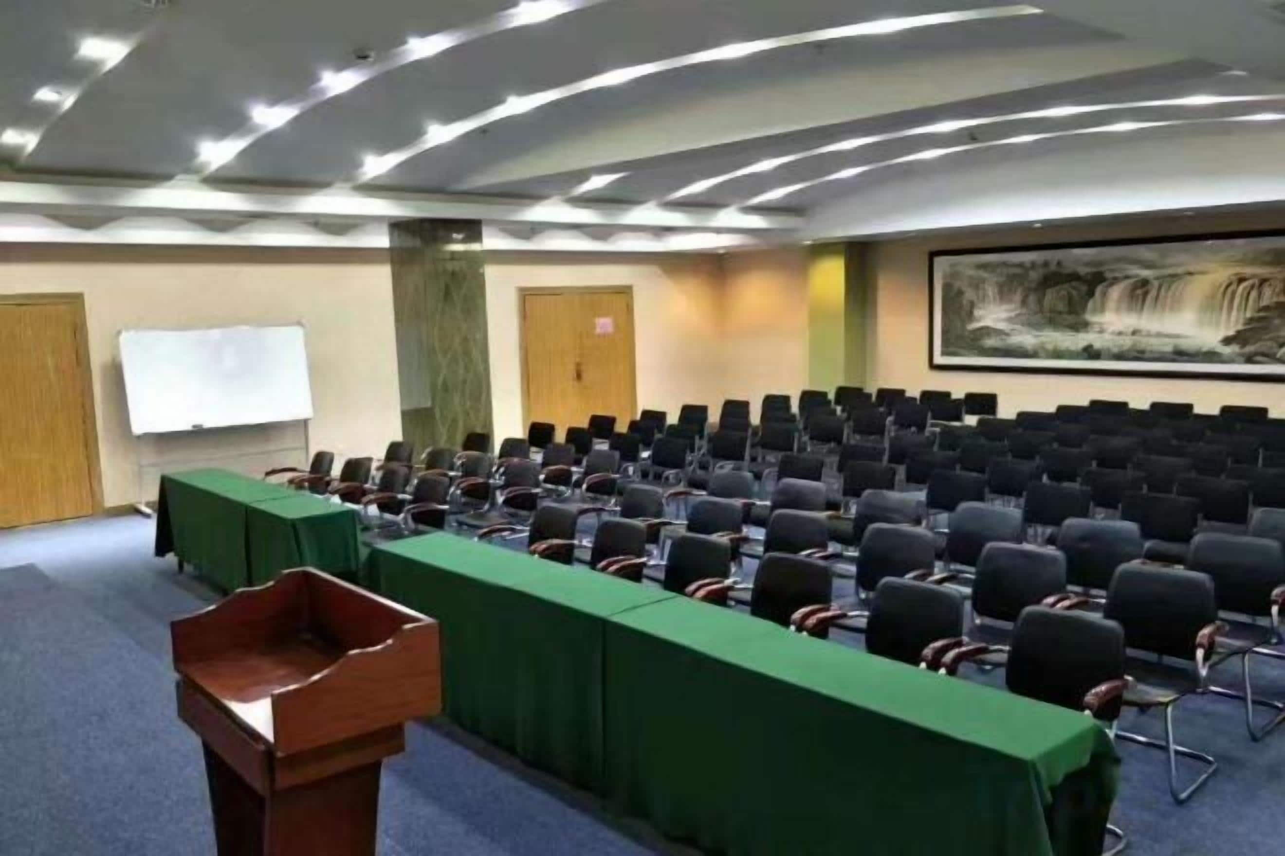 A conference room with rows of chairs, a podium, and a whiteboard.