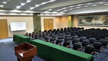 A conference room with rows of chairs, a podium, and a whiteboard.