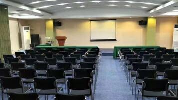 A conference room with rows of chairs, a podium, and a screen at the front.