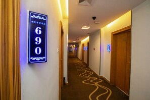 A hotel corridor with a sign indicating room number 690, a wooden door on the right, and a patterned carpet. - Silver Spring Hotel (Shenzhen Yuanling Subway Station) (Shenzhen)