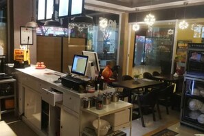 A restaurant interior with a counter, seating area, and a refrigerator. - Silver Spring Hotel (Shenzhen Yuanling Subway Station) (Shenzhen)
