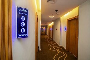 A hotel hallway with a sign indicating room number 690, wooden doors, and a patterned carpet.