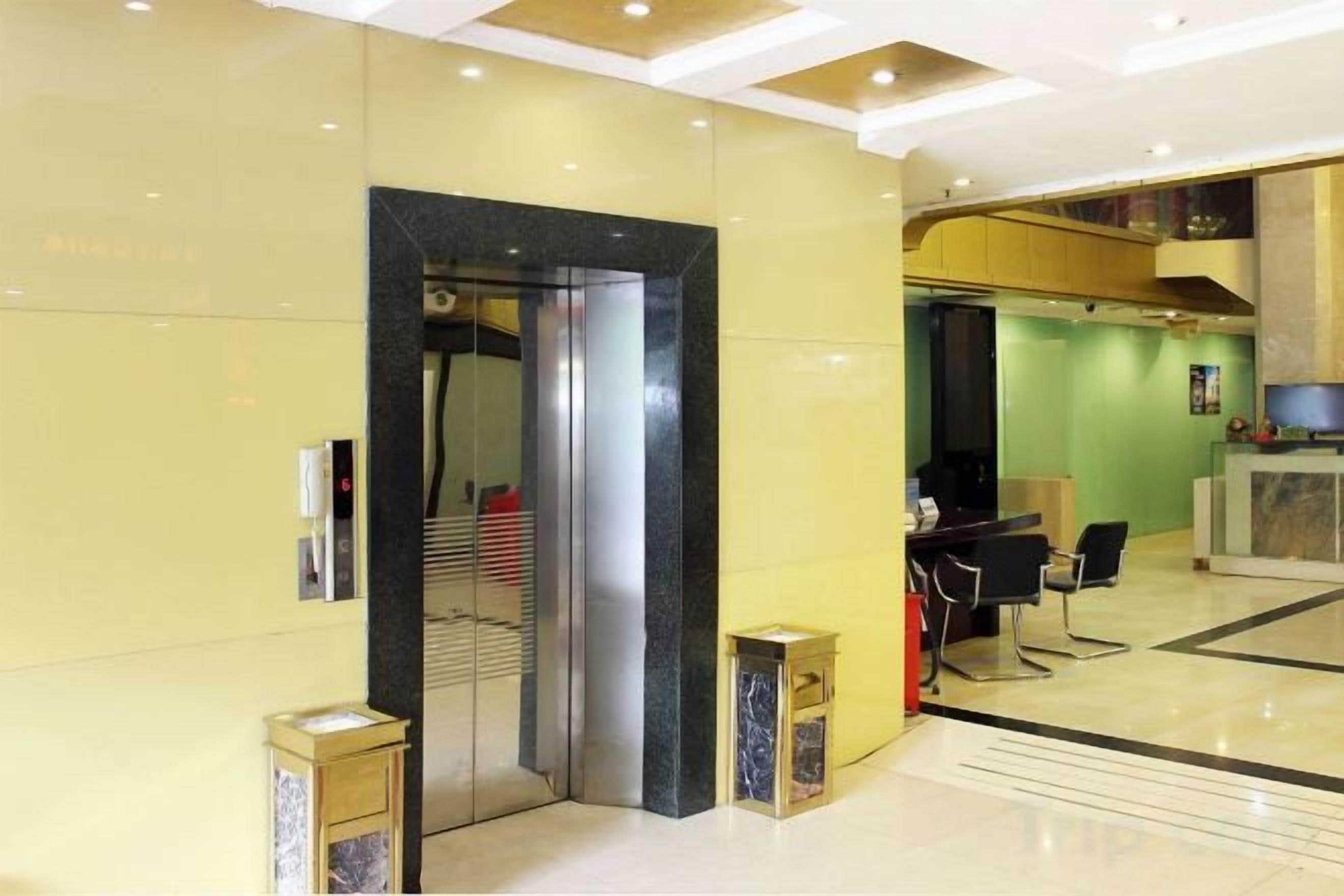 A hotel lobby with a reception desk, a seating area, and an elevator.