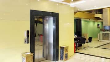 A hotel lobby with a reception desk, a seating area, and an elevator.