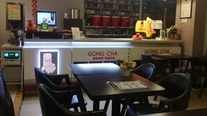 A restaurant interior with a counter, chairs, and a menu.