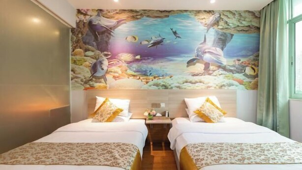 A hotel room with two beds, a mural of an underwater scene, and a nightstand with a lamp.