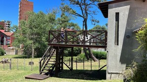Una escalera metálica conduce a una plataforma con sillas, rodeada de árboles y un edificio al fondo.