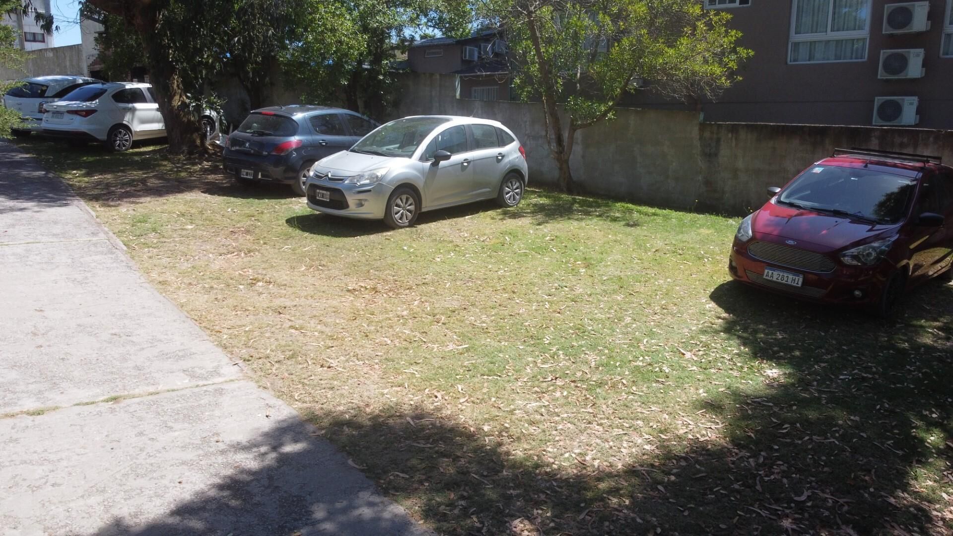 A parking area with several cars, including a silver hatchback and a red SUV.