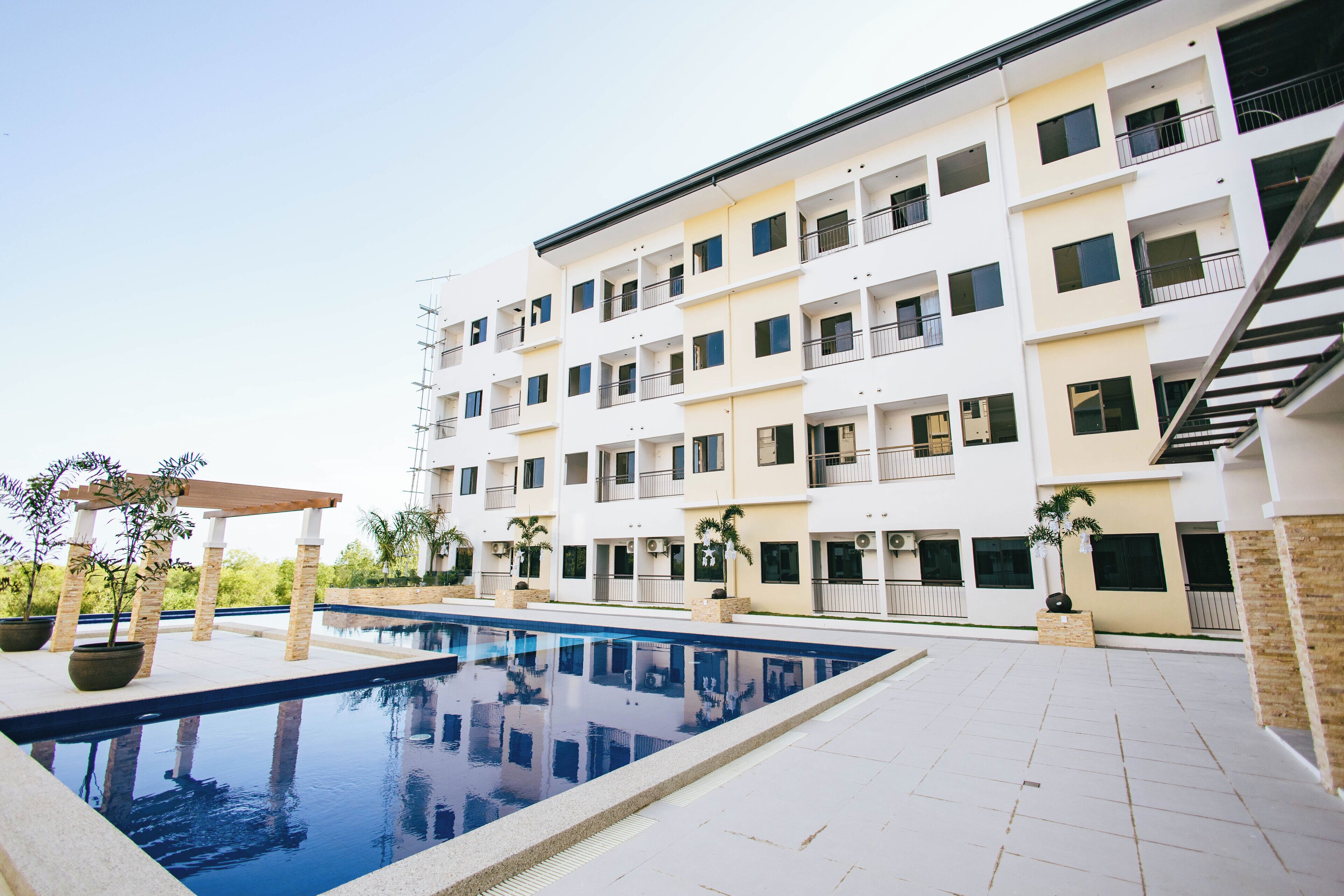 Un immeuble moderne à plusieurs étages, doté d’une piscine, d’un espace extérieur aménagé et de balcons.