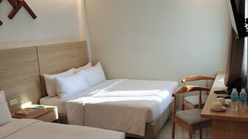 A hotel room with two beds, a desk, a chair, and a television.