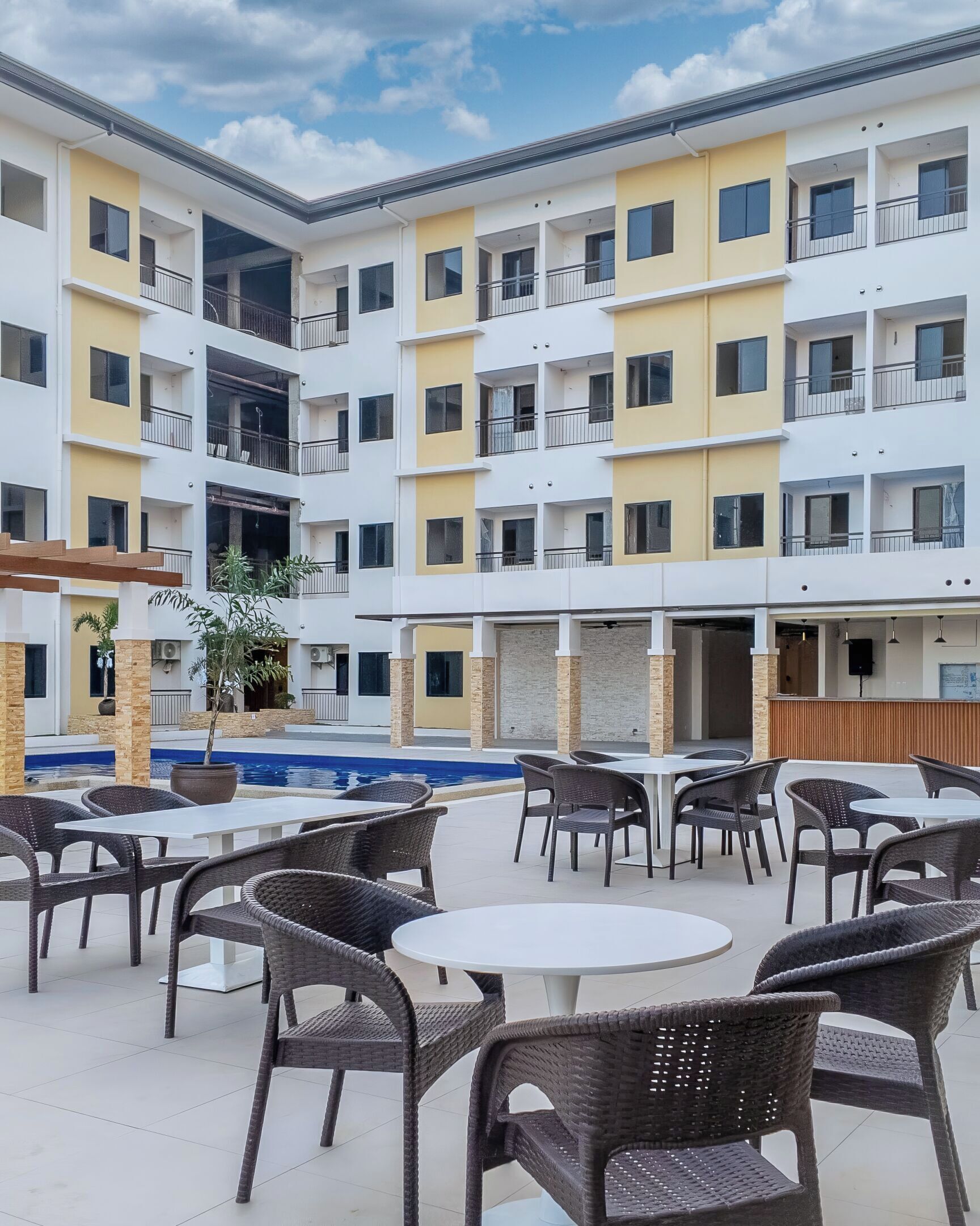 Un edificio de varios pisos con balcones, piscina y zonas de estar al aire libre.