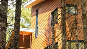 A modern wooden house with large windows and a glass extension, surrounded by trees. - Spa, Relaxation, Forest & River | Le Marmontin (sainte-christine-d'auvergne)