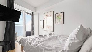 Une chambre à coucher avec un lit, un téléviseur et des œuvres d’art accrochées au mur.