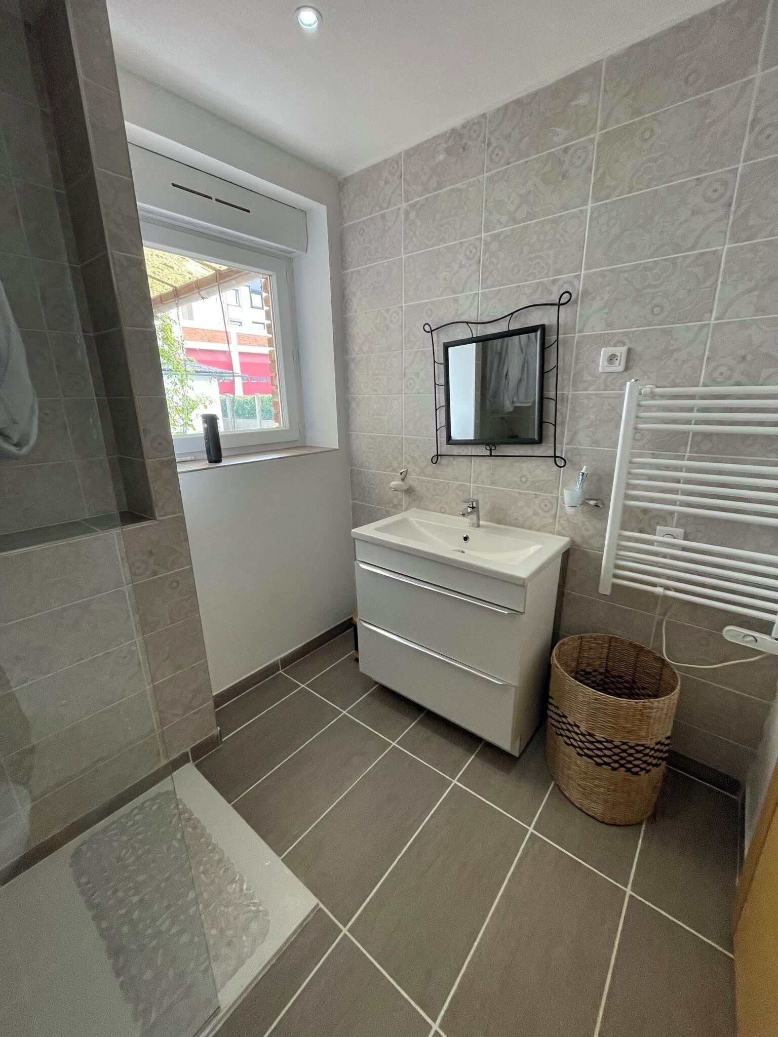 Une salle de bain moderne avec un lavabo blanc, un miroir et des murs carrelés.