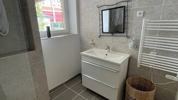 Une salle de bain moderne avec un lavabo blanc, un miroir et des murs carrelés.